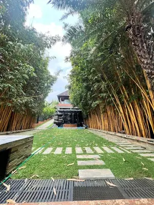 a garden with palm trees and a fence at Riverside Luxury Private Pool Villa in Athirappilly in Athirappally