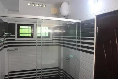 a bathroom with a glass shower with black and white tiles at Jewel Homes Thattekad For birding and families - An ISO9001 ISO14001 ISO22000 Certified in Thattakād