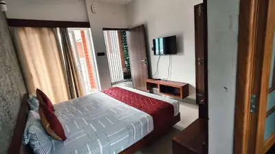 a bedroom with a bed and a tv and a window at Nelleri Residency Managed By Vaishno Hospitality in Iritti