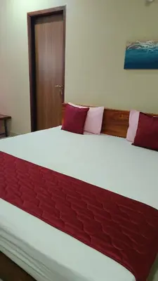 a bedroom with a large bed with red cushions at Nelleri Residency Managed By Vaishno Hospitality in Iritti