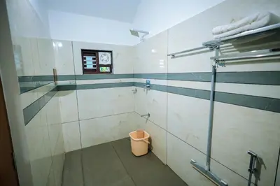 a bathroom with a glass shower with a trash can at Wayanadan Huts Homestay in Sultan Bathery