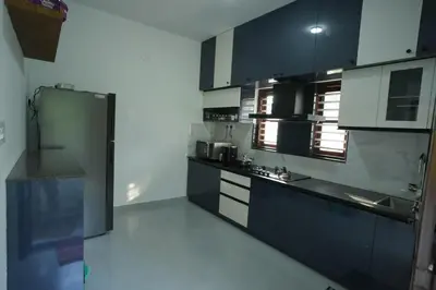 a kitchen with black and white cabinets in a room at Wayanadan Huts Homestay in Sultan Bathery