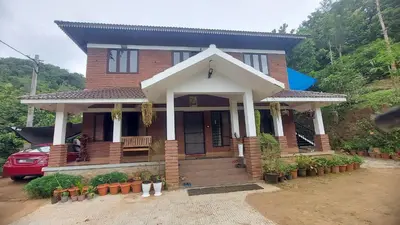 a house with a red car parked in front of it at Blue Hills View in Attappādi