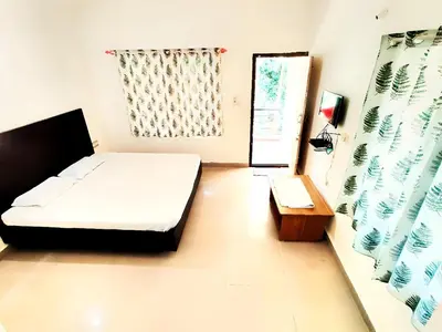 a bedroom with a bed and a table and a window at coorg Namana homestay in Suntikoppa