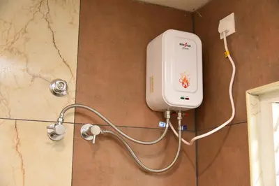 a shower in a bathroom with a hand dryer on a wall at sree ganesh inn in Palani