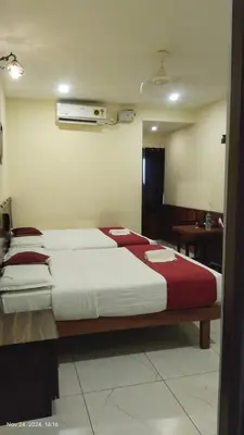 a bedroom with two beds with red and white sheets at sree ganesh inn in Palani