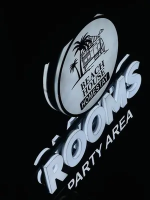 a sign for a restaurant with a palm tree at Beach House in Kozhikode