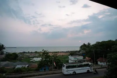 a white bus driving down a street next to a beach at Beach House in Kozhikode