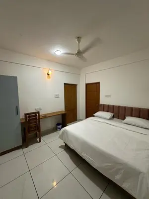 a bedroom with a large bed and a chair at Beach House in Kozhikode