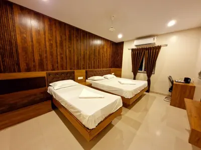 two beds in a room with wooden walls at Le Royal Suite in Udumalaippettai