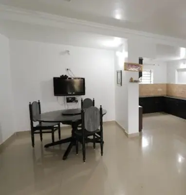 a dining room with a table and chairs and a tv at Maria villa in Ooty