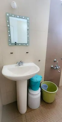 a bathroom with a sink and a mirror and a bucket at Maria villa in Ooty