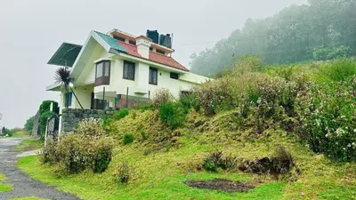 a house sitting on top of a grassy hill at Away From Home - 1 - Home Stay Ooty, Entire 3BHK Villa in Ooty