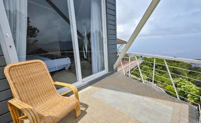 a wicker chair sitting on the balcony of a house at Ibex Resorts, Coonoor - Tapas in Yedapalli