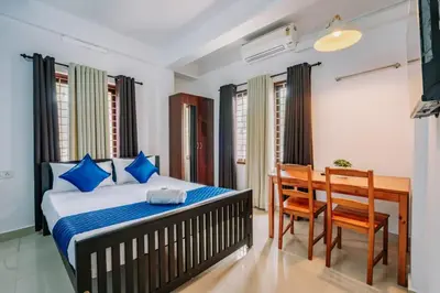a bedroom with a bed and a table and chairs at Holiday Homes Aluva in Alwaye
