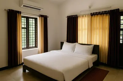 a bedroom with a white bed and two windows at Jacob's Homestay in Wayanad