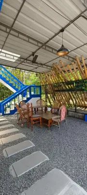 a patio with chairs and a table and blue stairs at Maryland homestay in Thattakād