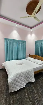 a bedroom with a large bed with blue curtains at Premium Service apartment in Mysore