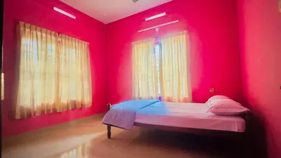 a red room with a bed in front of two windows at EV7 Stays in Trichūr
