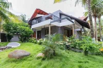 a house with a balcony and palm trees at Ekta Pool Farmstay Pollachi in Pollāchi