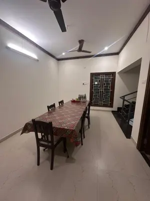 a dining room with a table and chairs and a ceiling fan at Kanchana Sirur home in Coimbatore