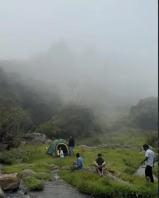 a group of people sitting in a field next to a tent at Muffintrip stays camp N trek in Kūkkāl