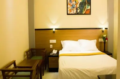 a bedroom with a bed and a desk with a phone at Kohinoor Hotels in Erode