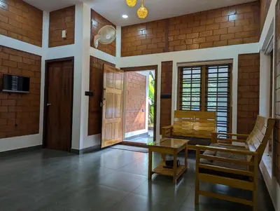 a room with a table and chairs and a door at DreamWoods Cottage in Kelakam