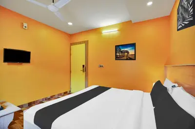 a bedroom with a bed with orange walls and a tv at Hotel O Kushal Nagar Near KSRTC Bus Stand in Kushālnagar