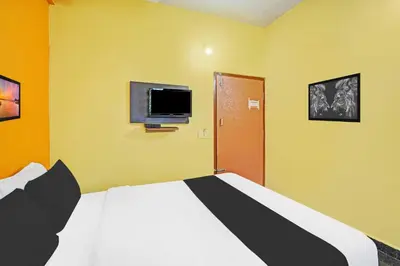 a bedroom with a bed and a tv on the wall at Hotel O Coorg Hanging Bridge in Kushālnagar