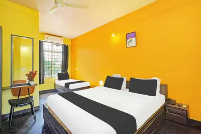 a bedroom with a large bed and a yellow wall at Hotel O Coorg Hanging Bridge in Kushālnagar