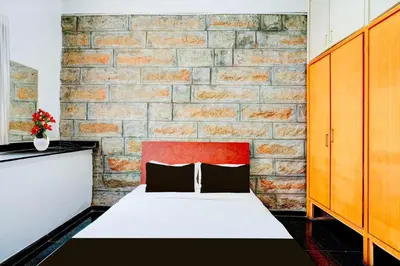 a bed in a room with a brick wall at Hotel O Mysuru Sand Museum in Mysore