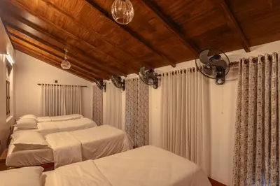 a bedroom with three beds and a wooden ceiling at The Oneness Living- Seasonal Heritage stay with Tholpaavakoothu nights in Pazhayannūr