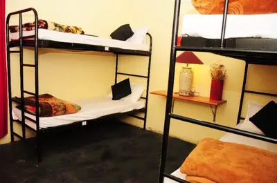 a room with three bunk beds and a lamp at Bykerstops in Ooty
