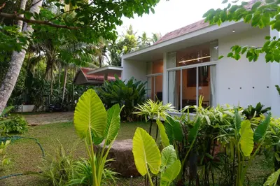 a white house with plants in front of it at Malhar - Your home away from home in Bālūssheri