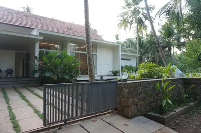 a house with a fence in front of it at Malhar - Your home away from home in Bālūssheri