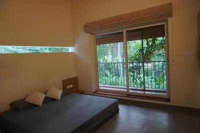 a bedroom with a bed and a large window at Malhar - Your home away from home in Bālūssheri
