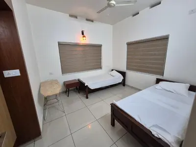 a bedroom with two beds and a table and a window at Zainab Apartment in Perintalmanna