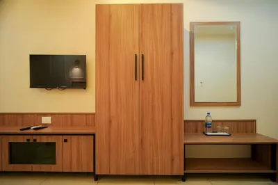 a large wooden cabinet with a television and a desk at AR Suites Kothamangalam in Kotamangalam