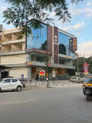 a large building with cars parked in front of it at AR Suites Kothamangalam in Kotamangalam