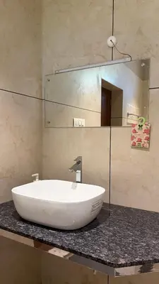 a bathroom with a white sink and a mirror at IRU Homes - Private Family Stay with Pool in Ambalavayal