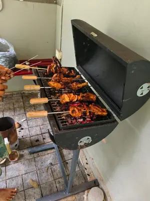 a grill with chickens and other food cooking on it at IRU Homes - Private Family Stay with Pool in Ambalavayal