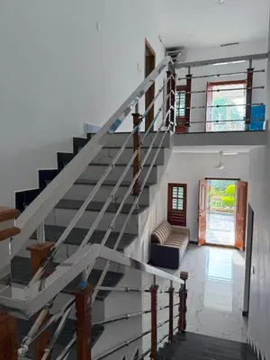 a staircase in a house with a living room at SRI Villa Rooms in Wayanad - Family Villa Stay with Mountain views in Vayittiri