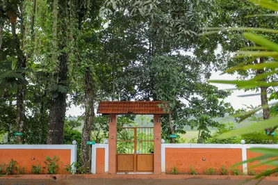 a gate in front of a fence with trees at Kudajadri Drizzle Homestay in Kaniyāmbetta