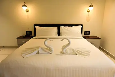 two white swans are sitting on a bed at Hotel S S International Coorg in Suntikoppa