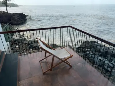 a chair sitting on a balcony overlooking the ocean at Coastline 4Bedroom cliffside villa in Elattūr