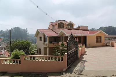 a house with a fence in front of it at Rainbow Cottages-Budget Friendly rooms in Ooty