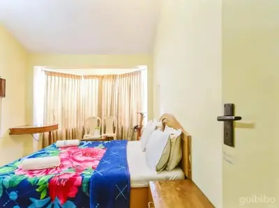 a bedroom with a bed with a colorful blanket at Rainbow Cottages-Budget Friendly rooms in Ooty