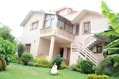 a dog sitting in front of a house at Rainbow Cottages-Budget Friendly rooms in Ooty