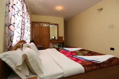 a bedroom with a bed with white sheets and a window at Rainbow Cottages-Budget Friendly rooms in Ooty